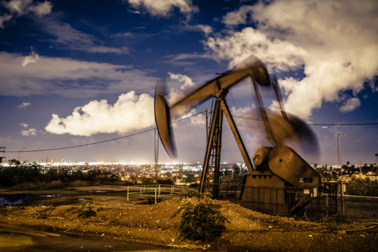 Photo of an oil pumpjack at the Inglewood Oil Field in the Baldwin Hills, overlooking the nighttime glow of the Westside of Los Angeles.