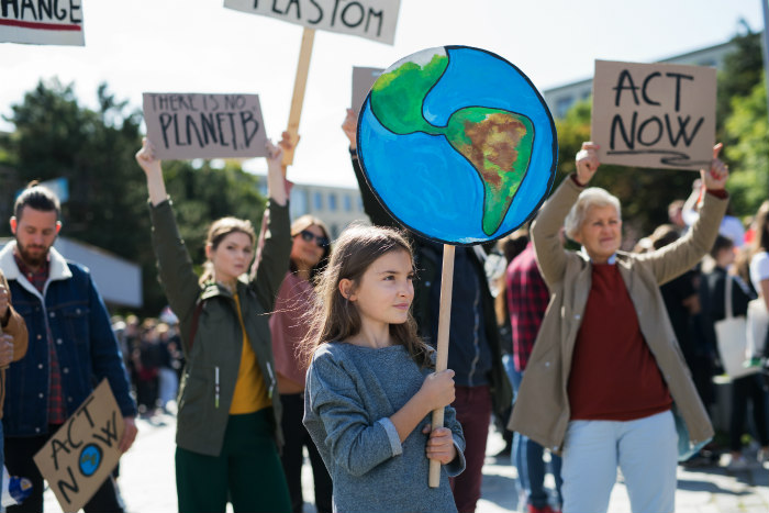 Climate change protest featuring a young girl holding a sign in the shape of planet Earth