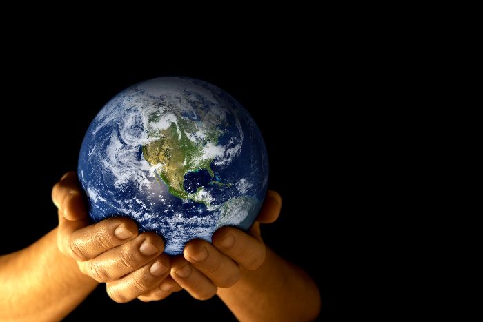 Hands holding planet earth against a black background