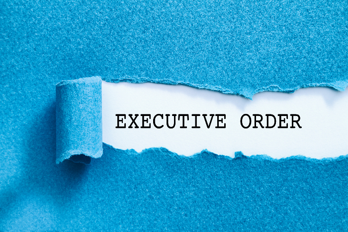 The phrase EXECUTIVE ORDER typewritten on white paper beneath a blue folder
