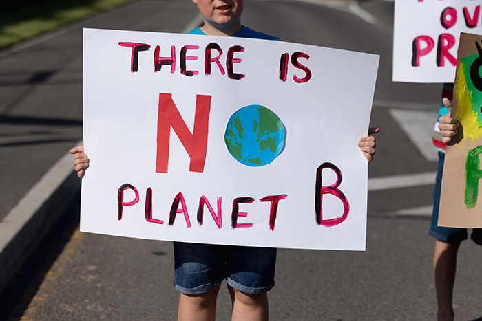 Photo of a boy holding up a sign that says "there is no planet b"