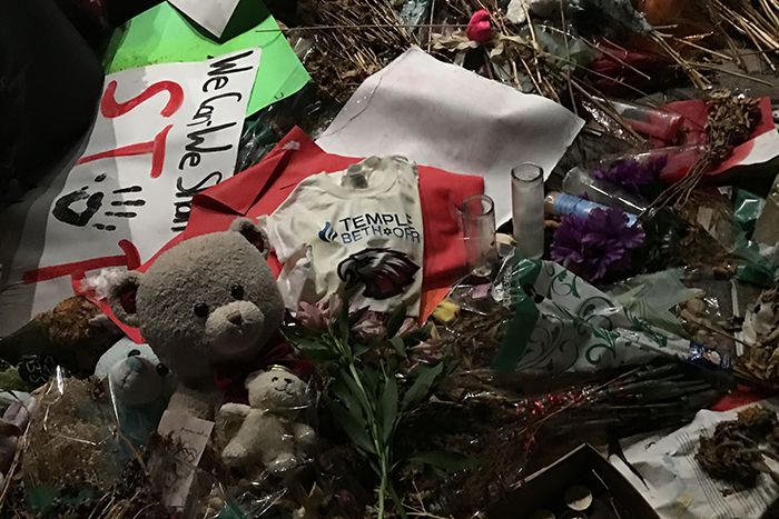 Photo of a memorial with a shirt, bear, sign that says STOP