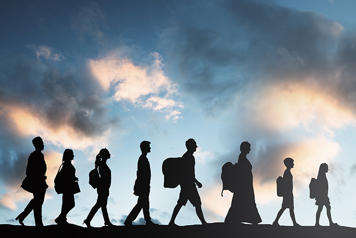 Photo of the silhouette of 8 people walking in a straight line wearing backpacks