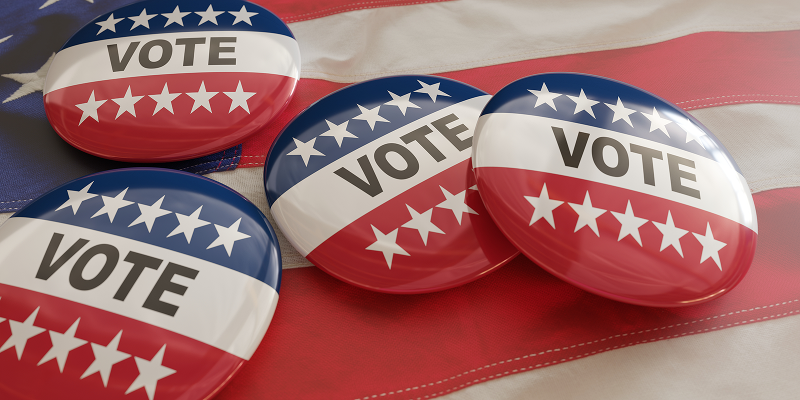 Photo of four red, white and blue pins that says VOTE laying on an American flag