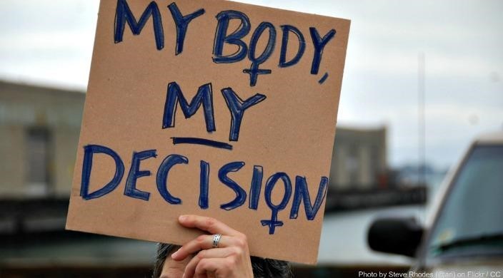 Hand holding sign that says "My body my decision"