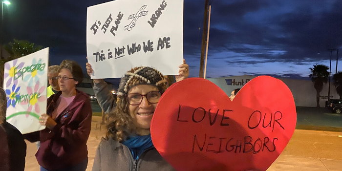 Woman holding "love our neighbors" sign