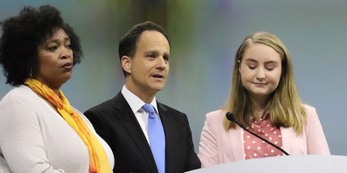 A man and two women standing at a podium 