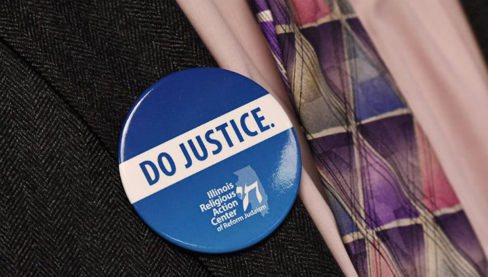 Closeup of a mans chest wearing a button that says DO JUSTICE
