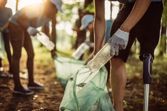 Closeup of peoples hands as they pick up trash in a park