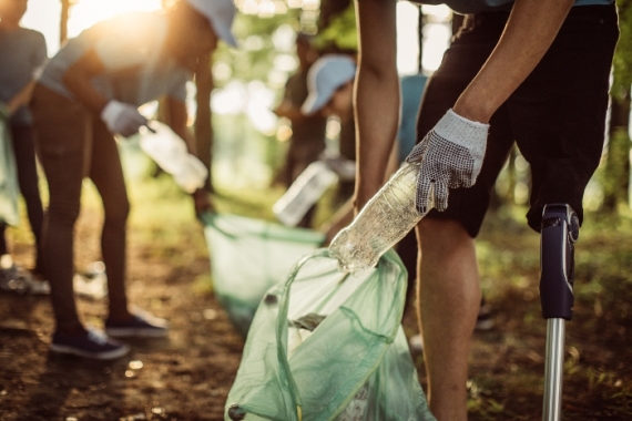 Closeup of peoples hands as they pick up trash in a park 