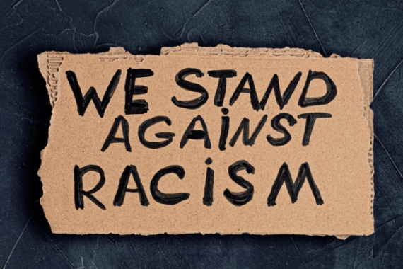 Cardboard sign reading WE STAND AGAINST RACISM