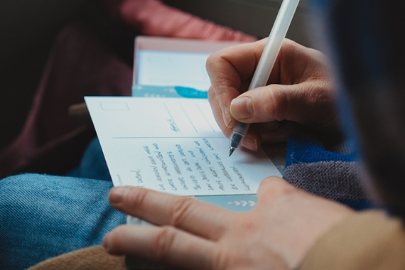 hand writing a postcard