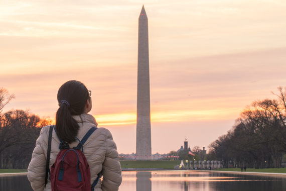 A person looking at the Washington Monument at sunset