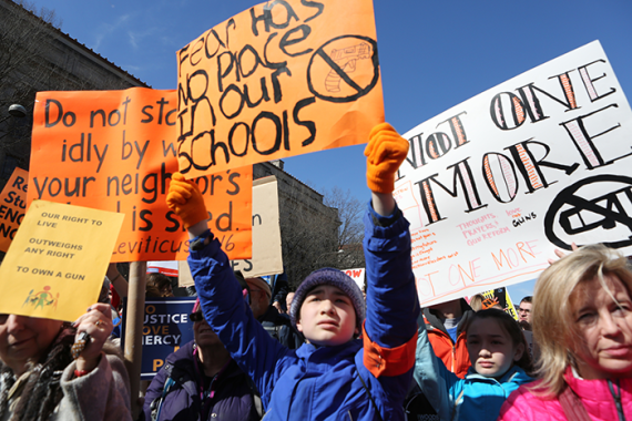 an image from a RAC Gun Violence Prevention rally in 2018, March for Our Lives; boy holding up oranage sign with black letters that says "Fear has no place in our schools"