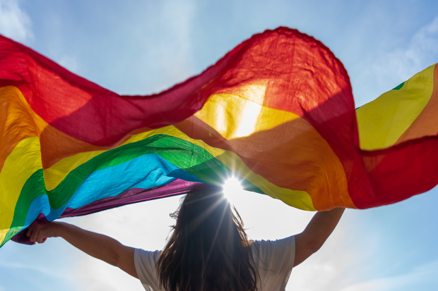 Photo of a young woman waving LGBTQ+flag