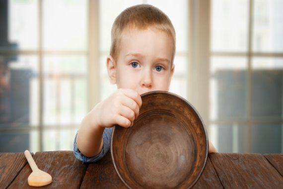 Small boy holding empty bowl signifying hunger