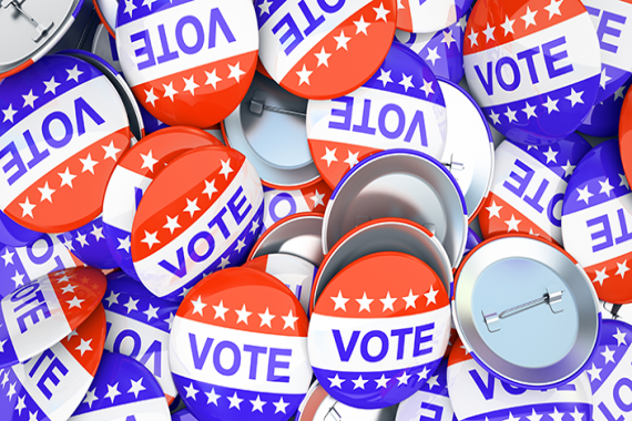 A pile of red, white, and blue buttons that say Vote