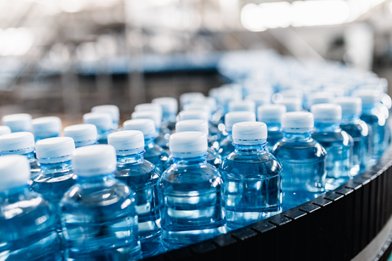 Photo of plastic water bottles on conveyer belt in processing plant
