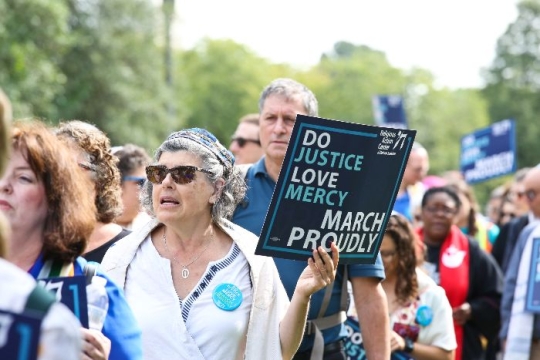 Group of people marching in a protest holding a RAC sign