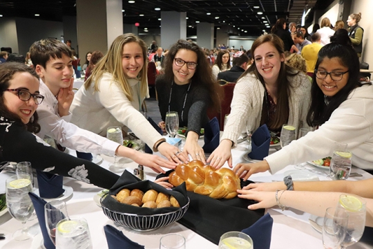 LTaken participants blessing challah at Shabbat dinner