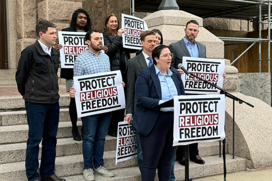 Photo of Emily Bourgeois, RAC-TX, speaking out the capitol building in Austin, TX
