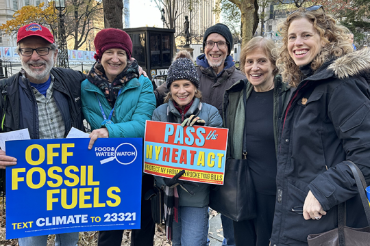 Photo of six people at a RAC rally; two holding signs that say "Pass the NY Heat Act" and "Off Fossils Fuels"