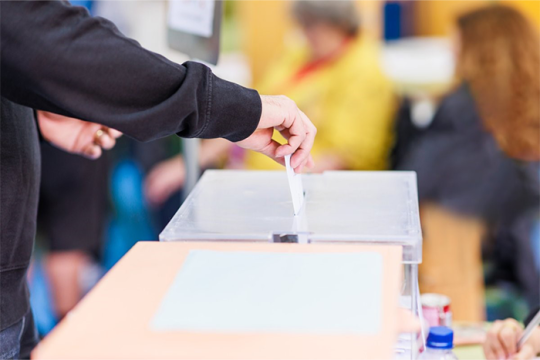 A hand putting a ballot in a ballot box