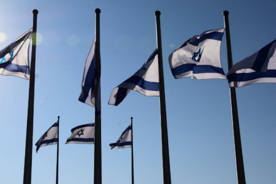 A few Israeli flags on flagpoles against a blue sky background