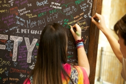 Two teens writing on a chalkboard about what NFTY means to them 