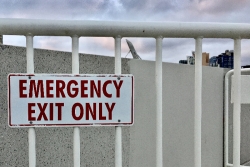 White railing with an EMERGENCY EXIT ONLY sign in red