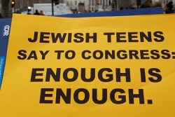 Hand holding sign in front of Capitol building that says Jewish Teens Say to Congress: Enough is Enough