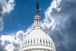 Dome of the US Capitol Building against a blue sky with clouds 