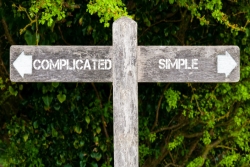 Wooden sign pointing on two directions that read SIMPLE and COMPLICATED
