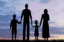 Silhouette of a family standing against sunset