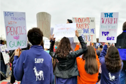 Teens with their bck to the camera holding gun violence prevention signs at March for Our Lives 