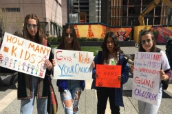Four somber teen girls holding handmade gun violence prevention signs 