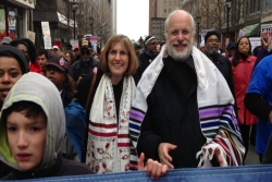 Rabbi Fred Guttman and Rabbi Lucy Dinner wearing Jewish prayer shawls while marching in a rally