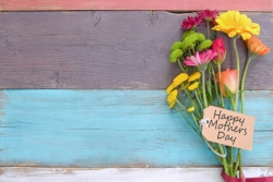 Bouquet of flowers with ribbon and Mother's Day tag standing in front of striped painted wall