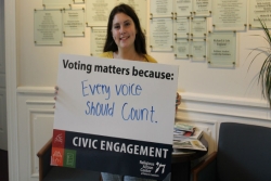 Young woman holding a sign that reads Voting counts because every voice should matter 