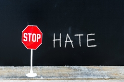 Stop sign next to the word HATE written on a chalkboard 