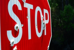 Closeup of a stop sign riddled with bullets