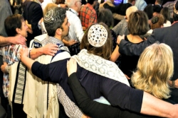 People with their arms around one another from the back wearing kippot