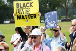 A priest and a rabbi holding signs about justice and Black Lives Matter in a large group of protesters 