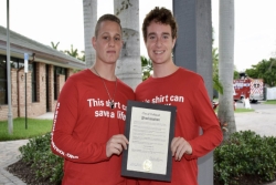 Two teen boys holding an award and wearing matching red tees that say THIS SHIRT CAN SAVE A LIFE