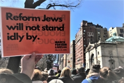 Person holding a sign saying "Reform Jews will not stand idly by"