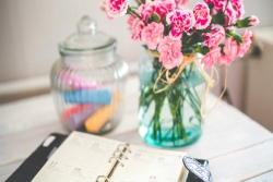 Desk with pink flowers and an open planner set on top of it 